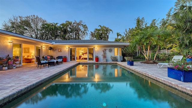 pool at dusk featuring a patio