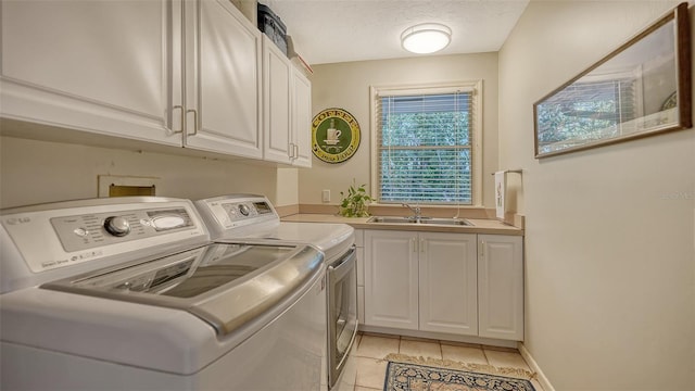 laundry room with sink, cabinets, washer and clothes dryer, light tile patterned floors, and a textured ceiling