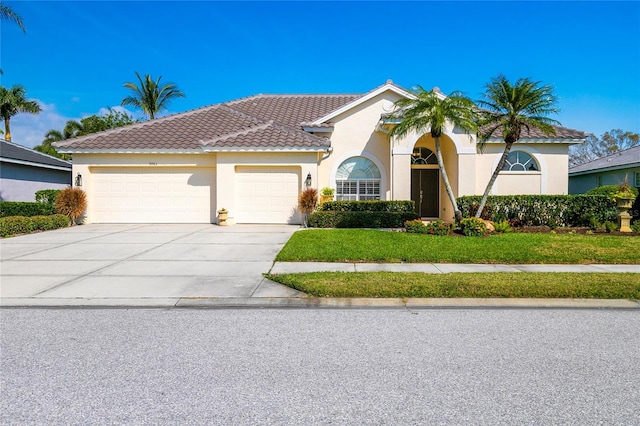 mediterranean / spanish home featuring a garage and a front lawn