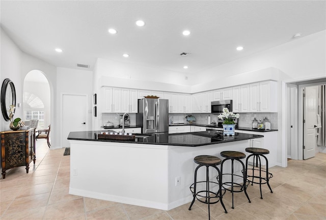 kitchen featuring a large island, sink, a breakfast bar area, stainless steel appliances, and white cabinets