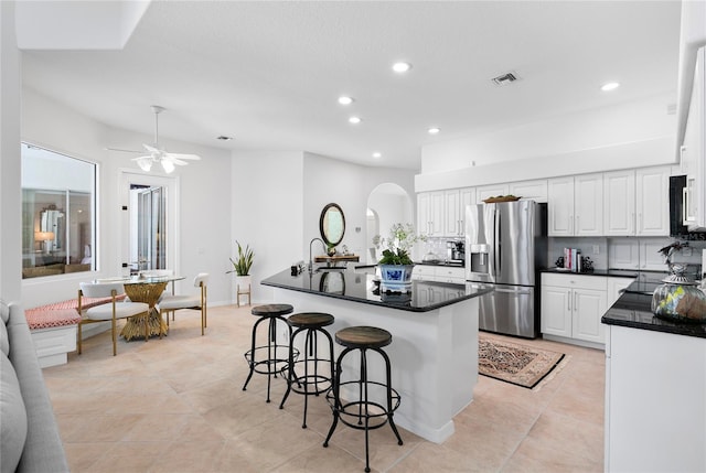 kitchen featuring a kitchen island, white cabinetry, a breakfast bar area, decorative backsplash, and stainless steel refrigerator with ice dispenser