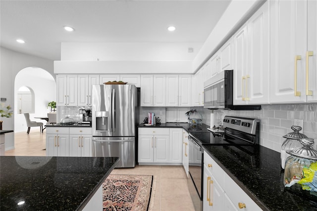 kitchen with appliances with stainless steel finishes, dark stone countertops, white cabinets, and light tile patterned floors