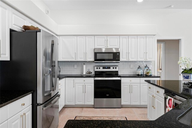 kitchen featuring white cabinetry, stainless steel appliances, and dark stone counters