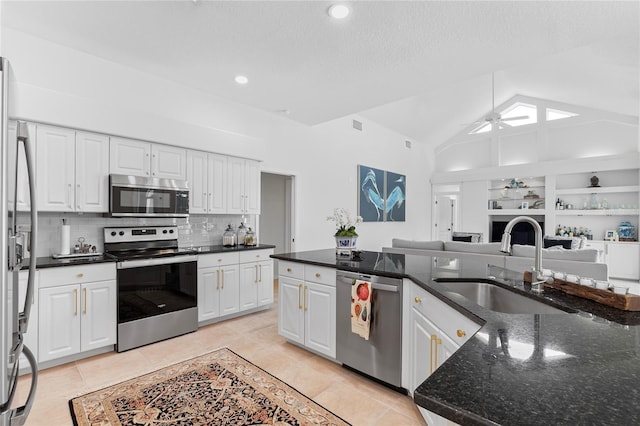 kitchen with sink, ceiling fan, white cabinetry, stainless steel appliances, and dark stone counters