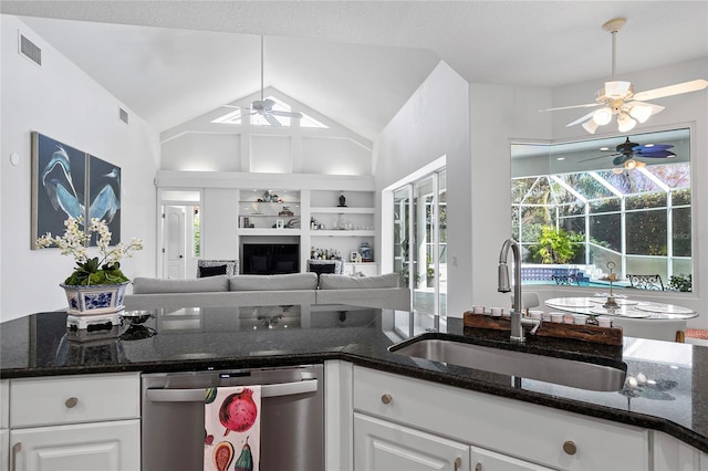 kitchen featuring white cabinetry, sink, stainless steel dishwasher, and dark stone counters