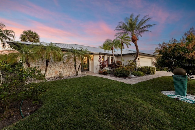 single story home featuring a garage and a yard