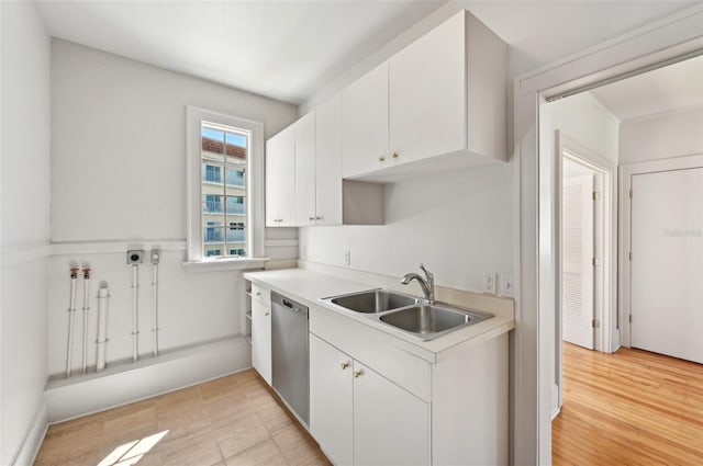 kitchen with light countertops, stainless steel dishwasher, light wood-style floors, white cabinets, and a sink