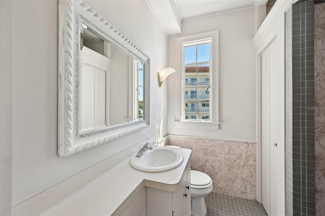 bathroom featuring vanity, a wainscoted wall, ornamental molding, tile walls, and toilet