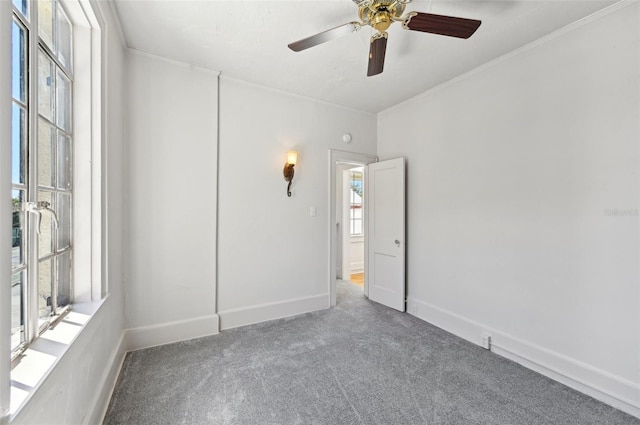 carpeted empty room with crown molding, a ceiling fan, and baseboards