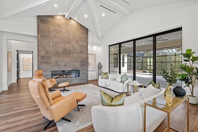 living room featuring hardwood / wood-style flooring, a tiled fireplace, high vaulted ceiling, and beamed ceiling