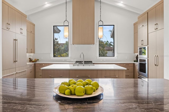 kitchen with paneled refrigerator, decorative light fixtures, vaulted ceiling, and a kitchen island