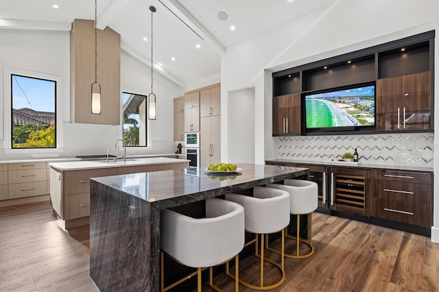 bar featuring pendant lighting, hardwood / wood-style flooring, backsplash, beam ceiling, and dark stone counters