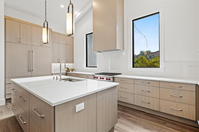 kitchen featuring light brown cabinetry, sink, gas stovetop, pendant lighting, and a kitchen island with sink