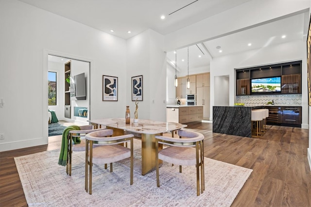 dining space featuring hardwood / wood-style floors, a towering ceiling, and sink