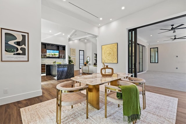 dining space featuring hardwood / wood-style flooring, ceiling fan, and bar area