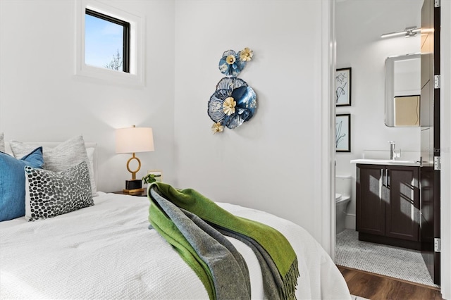 bedroom with connected bathroom, dark hardwood / wood-style floors, and sink