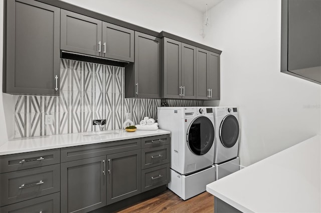 laundry area featuring cabinets, dark hardwood / wood-style floors, separate washer and dryer, and sink