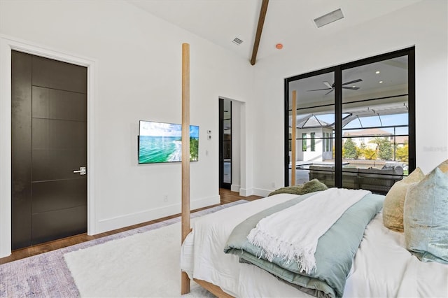 bedroom featuring hardwood / wood-style floors, access to outside, and lofted ceiling with beams