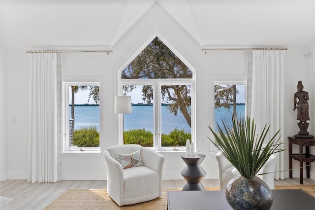 sitting room with a water view, vaulted ceiling, and light hardwood / wood-style flooring