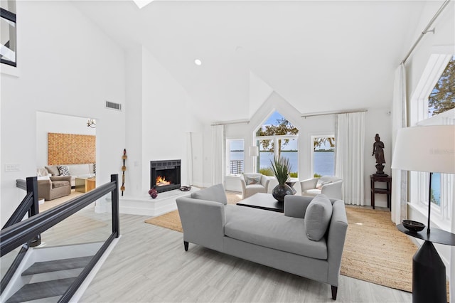 living room with a water view, a towering ceiling, and light wood-type flooring