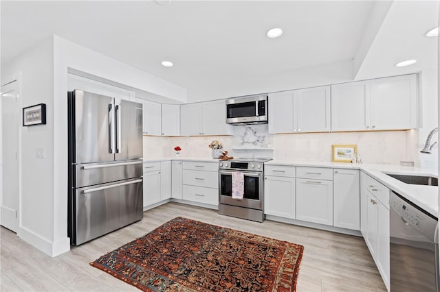 kitchen with sink, white cabinets, backsplash, light hardwood / wood-style floors, and stainless steel appliances