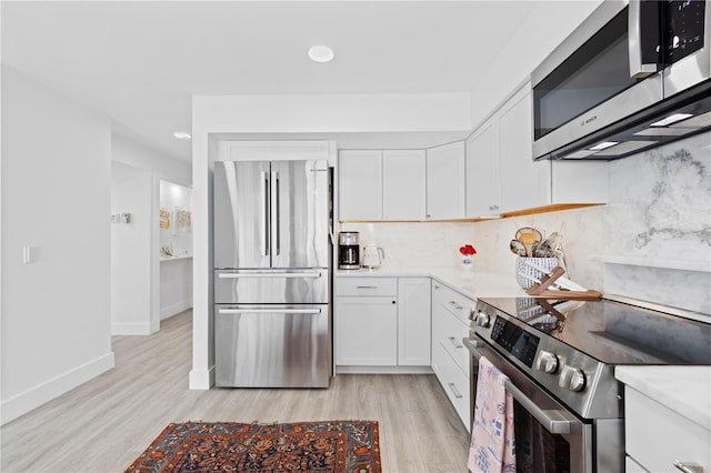 kitchen featuring white cabinetry, tasteful backsplash, stainless steel appliances, and light hardwood / wood-style flooring