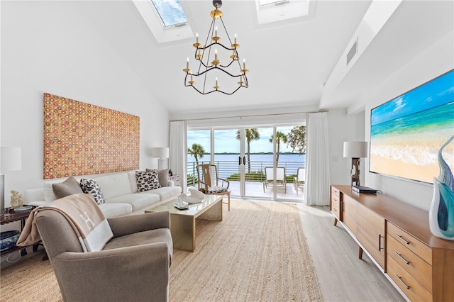 living room with high vaulted ceiling, a skylight, light hardwood / wood-style floors, and a chandelier