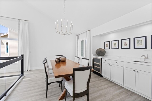 dining space featuring wine cooler, sink, light hardwood / wood-style flooring, and an inviting chandelier