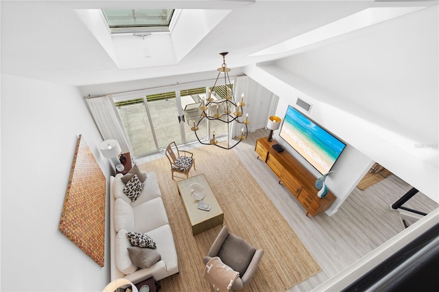 living room featuring hardwood / wood-style flooring, a chandelier, and a skylight