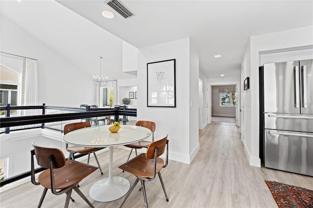 dining room featuring lofted ceiling, light hardwood / wood-style floors, and a chandelier