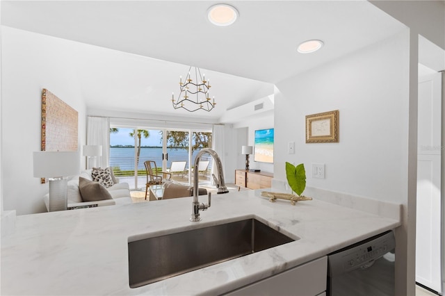 kitchen featuring sink, a water view, light stone countertops, stainless steel dishwasher, and a chandelier