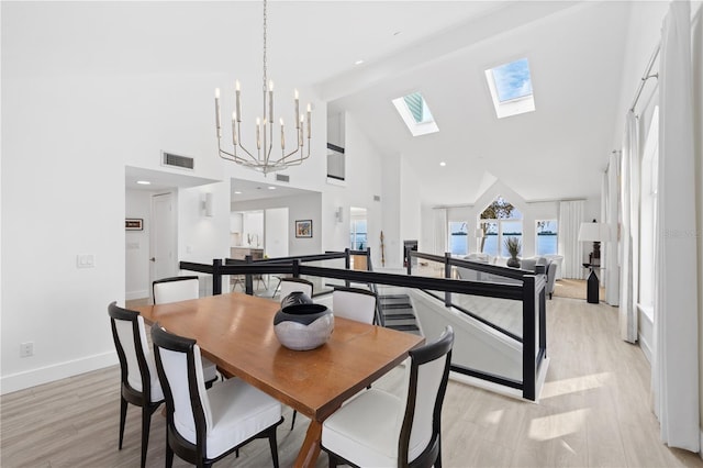 dining room with high vaulted ceiling, a chandelier, light hardwood / wood-style floors, and a skylight