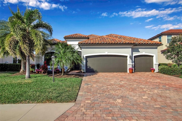 mediterranean / spanish-style home featuring a garage and a front yard