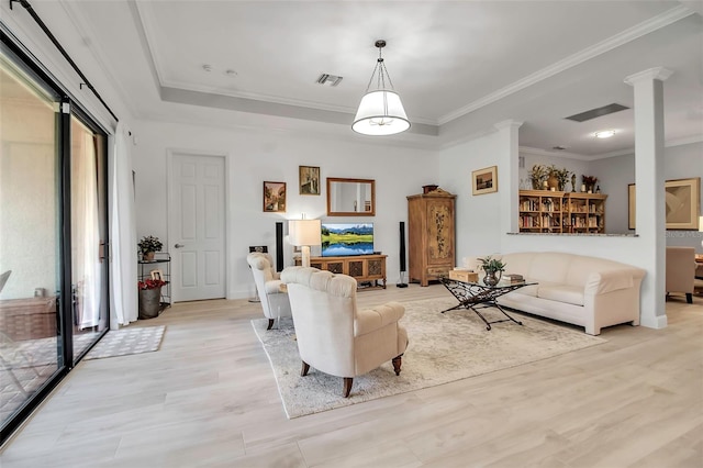 living room featuring ornamental molding, a healthy amount of sunlight, light hardwood / wood-style flooring, and ornate columns