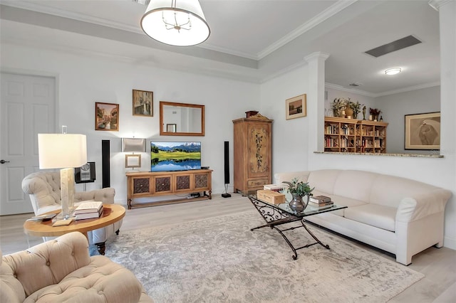 living room with decorative columns, ornamental molding, and light wood-type flooring