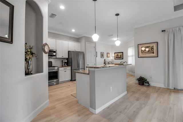 kitchen featuring white cabinetry, stone countertops, hanging light fixtures, stainless steel appliances, and light hardwood / wood-style floors