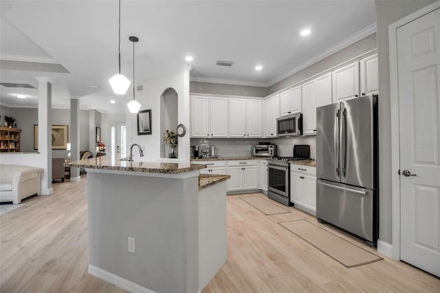 kitchen with stainless steel appliances, white cabinetry, pendant lighting, and light stone counters