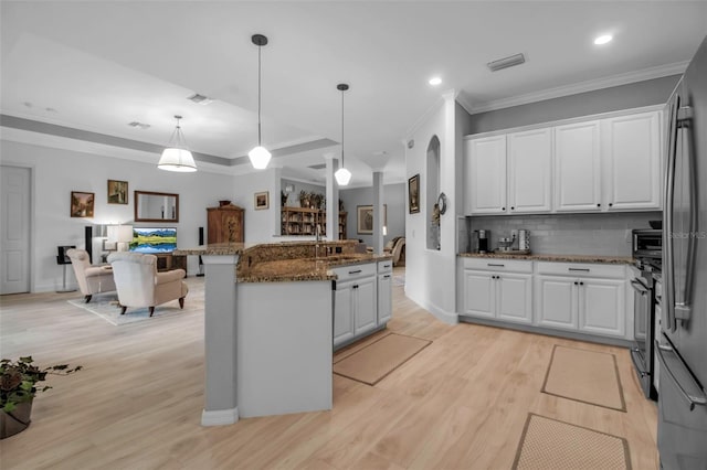 kitchen featuring pendant lighting, appliances with stainless steel finishes, white cabinetry, dark stone countertops, and light wood-type flooring