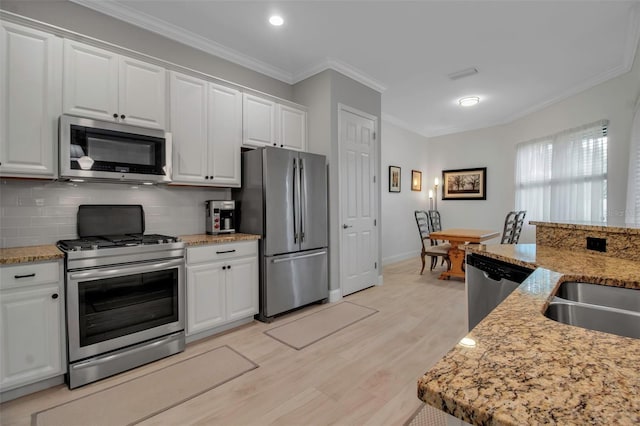 kitchen featuring tasteful backsplash, ornamental molding, stainless steel appliances, and white cabinets