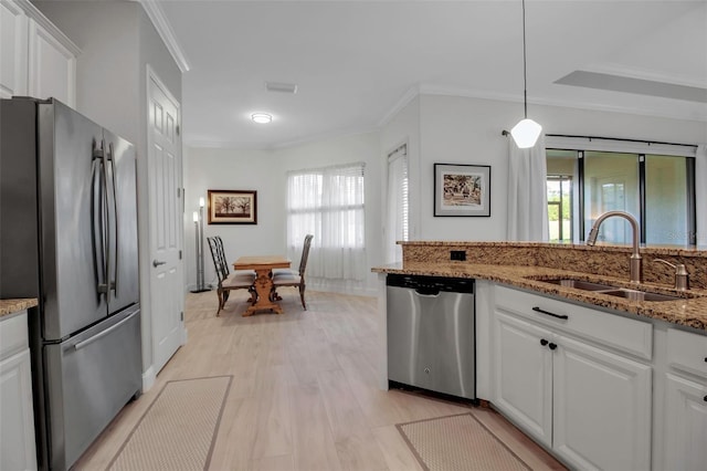 kitchen with sink, stainless steel appliances, light stone counters, white cabinets, and decorative light fixtures