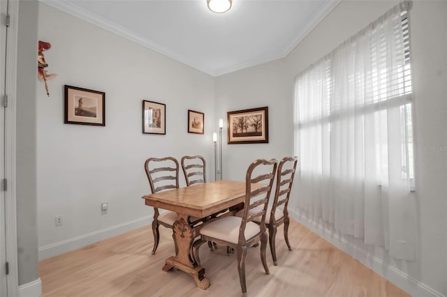 dining area with ornamental molding and light hardwood / wood-style flooring