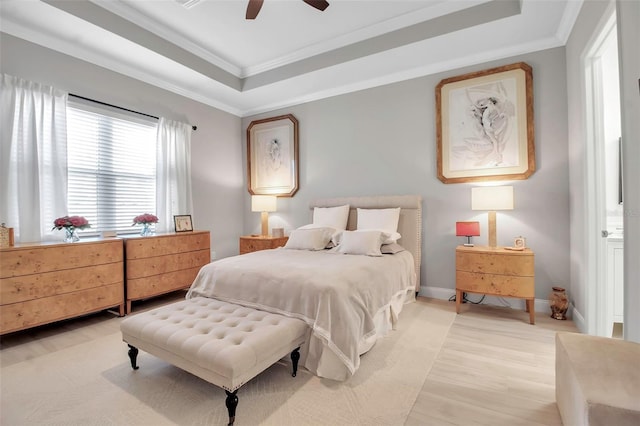 bedroom with ornamental molding, ceiling fan, light hardwood / wood-style floors, and a tray ceiling