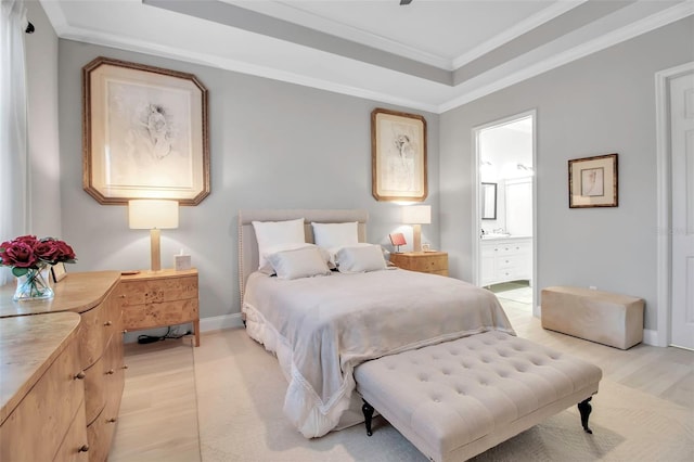 bedroom featuring ornamental molding, ensuite bathroom, a raised ceiling, and light wood-type flooring