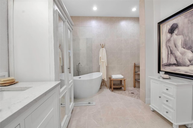 bathroom with vanity, tile patterned floors, tile walls, and a bathing tub