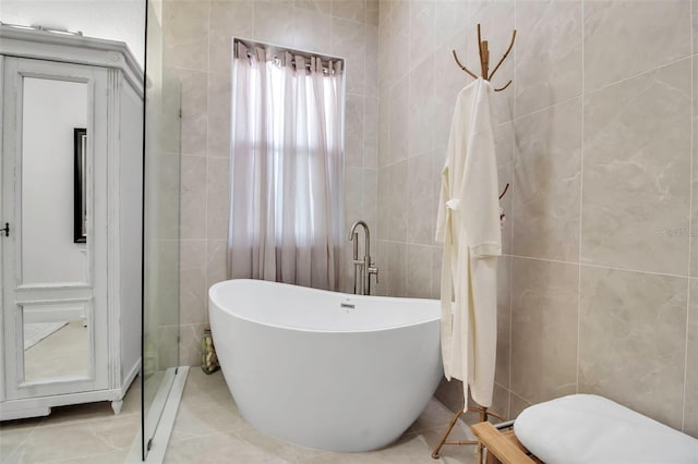 bathroom featuring tile walls, a tub to relax in, and tile patterned flooring