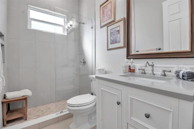 bathroom with vanity, toilet, and a tile shower