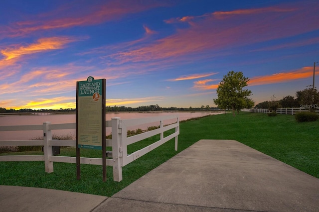 gate at dusk with a water view and a lawn