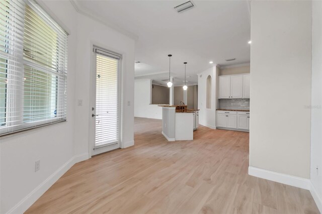 13303 Swiftwater Way, Lakewood Ranch, FL 34211 - unfurnished living room with baseboards, light wood-style floors, arched walkways, a sink, and crown molding