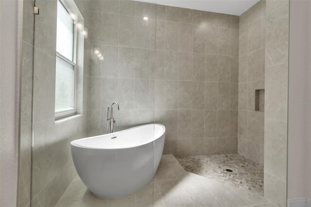 13303 Swiftwater Way, Lakewood Ranch, FL 34211 - full bathroom featuring healthy amount of natural light, a freestanding bath, tile walls, tile patterned flooring, and tiled shower
