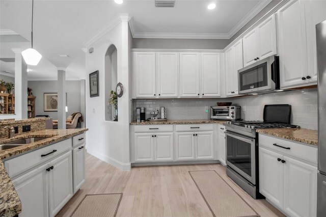 13303 Swiftwater Way, Lakewood Ranch, FL 34211 - kitchen featuring appliances with stainless steel finishes, white cabinets, tasteful backsplash, light wood-type flooring, and light stone counters